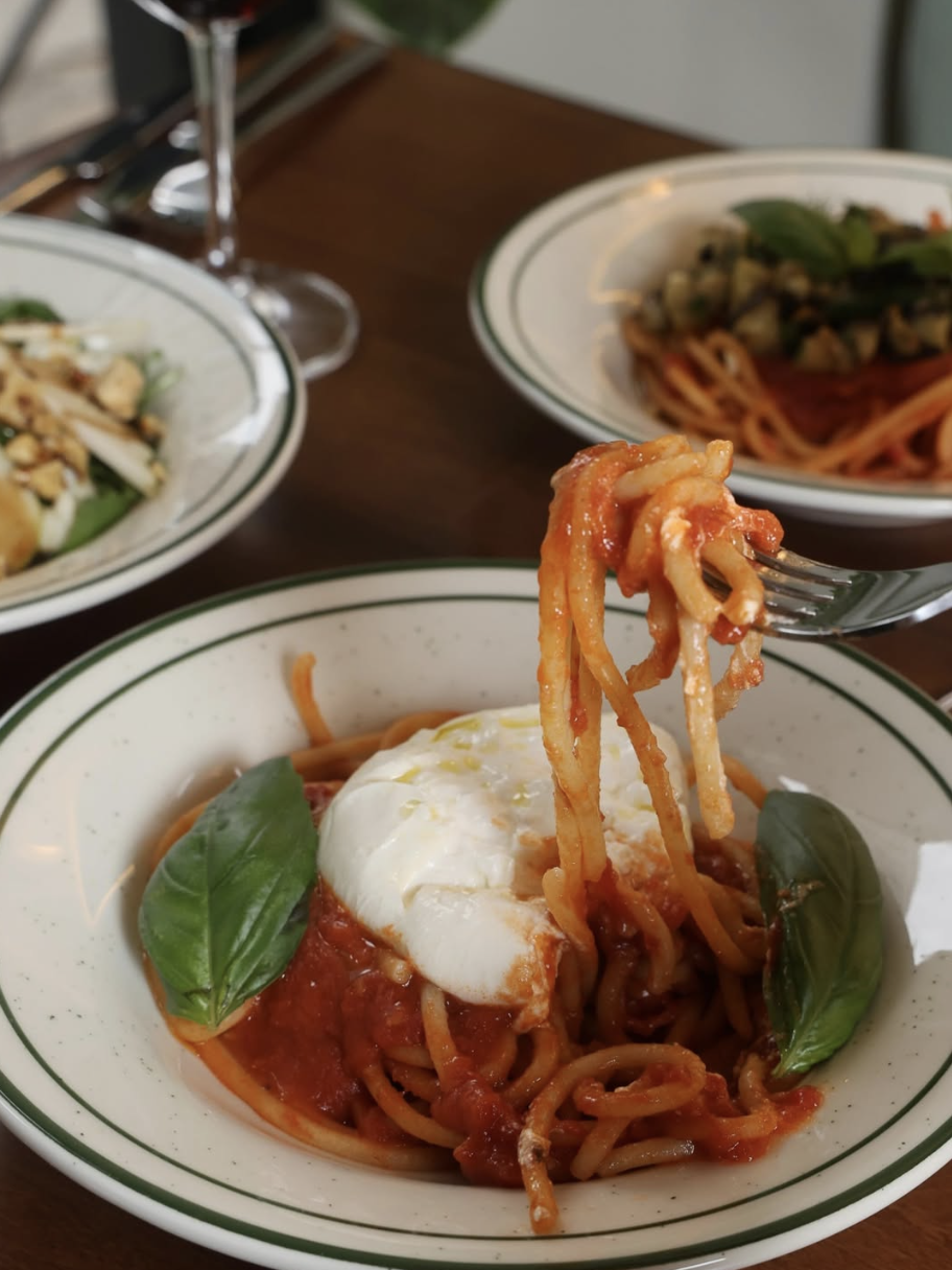Fresh Bigoli lifted on a fork with tomato sauce and burrata